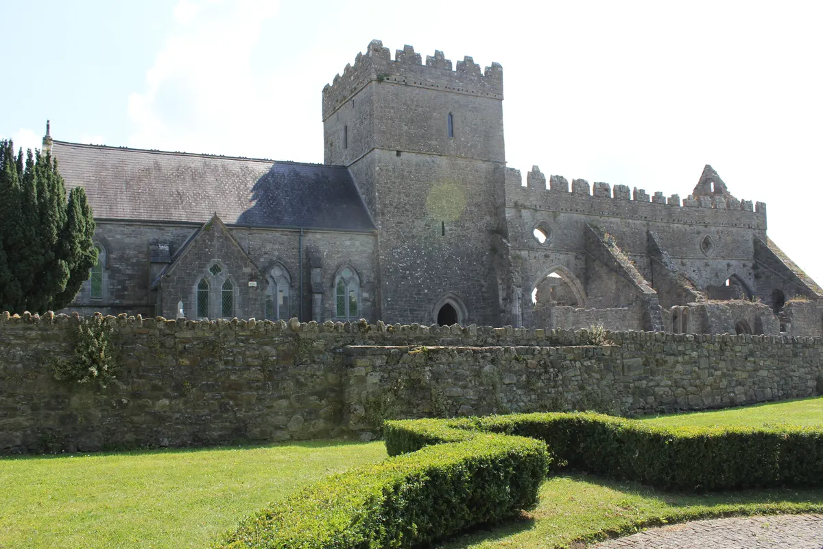 St Mary's Collegiate Church in Gowran, Co. Kilkenny, a medieval tower and ruined nave behind a stone wall