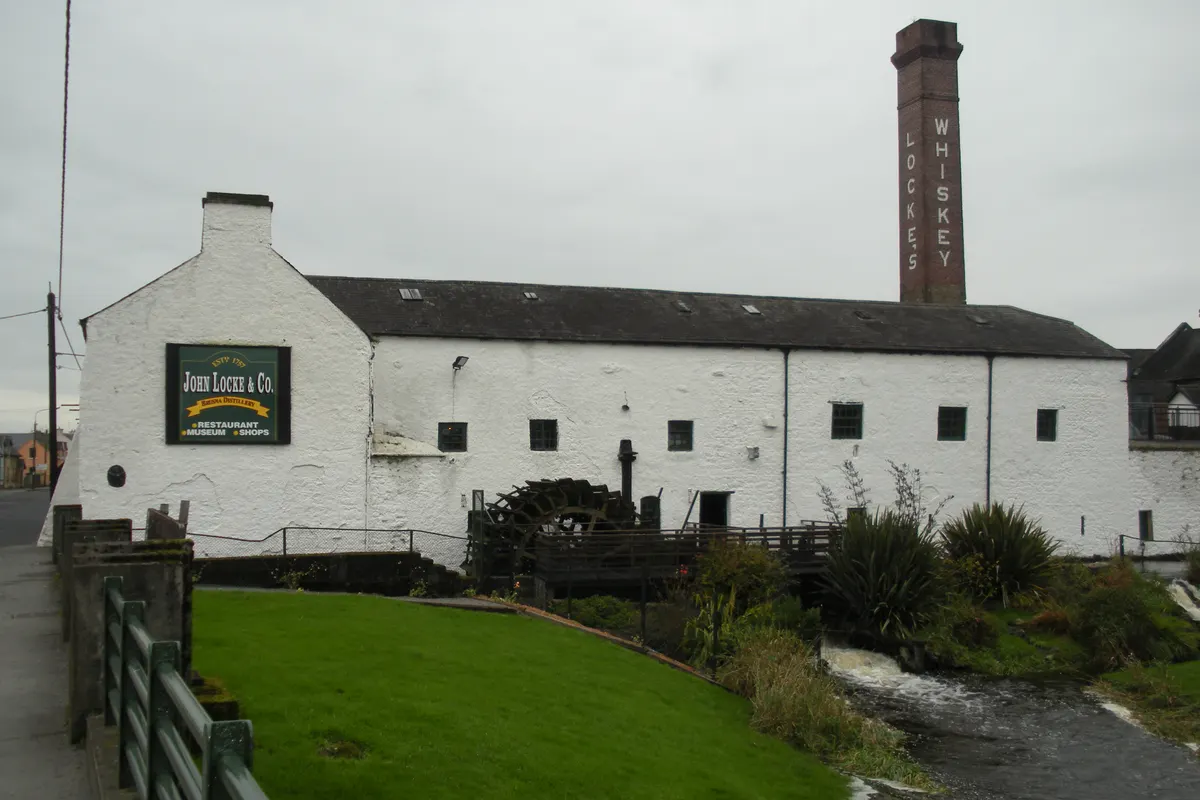 The whitewashed Locke's Distillery in Kilbeggan with its brick whiskey chimney and water wheel beside the River Brosna